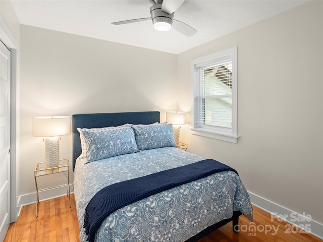 bedroom with a ceiling fan, wood finished floors, and baseboards