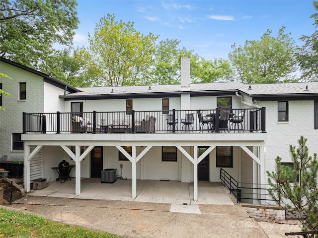 back of property with central AC unit, roof with shingles, a chimney, a patio area, and brick siding