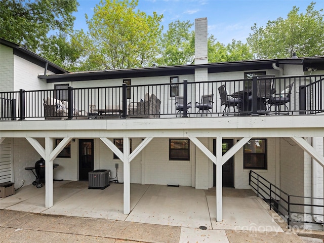 rear view of property with a patio area, a wooden deck, central AC unit, and a chimney