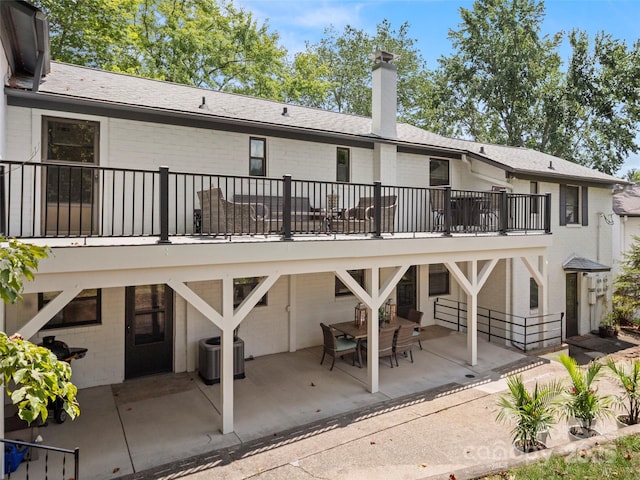 rear view of property with a patio area, central AC, a chimney, and brick siding