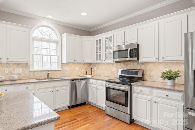 kitchen with a sink, light wood finished floors, appliances with stainless steel finishes, and white cabinetry