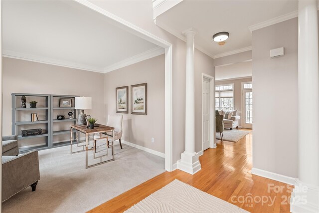 office space with light wood finished floors, baseboards, crown molding, and ornate columns