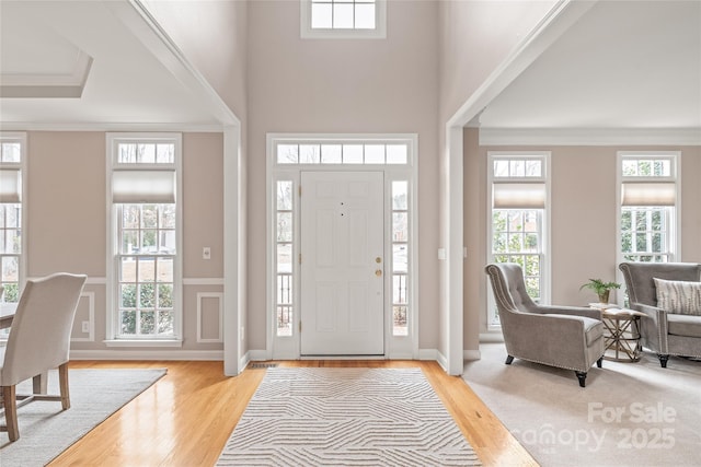 foyer entrance with plenty of natural light, light wood-style floors, and ornamental molding