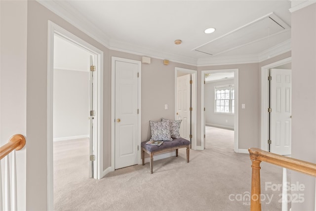 corridor featuring baseboards, light carpet, attic access, and crown molding