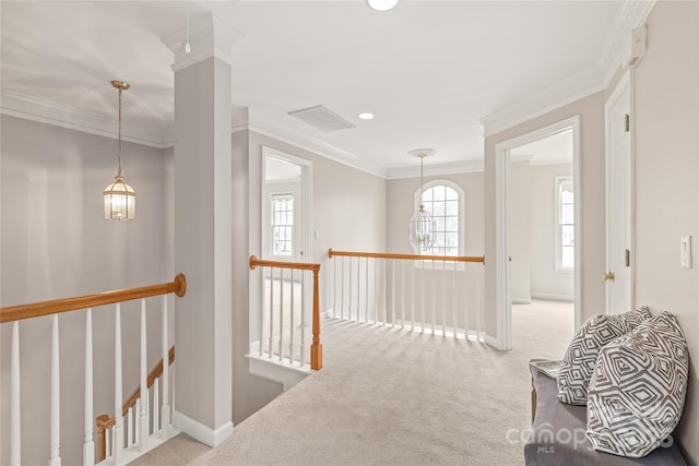 hallway with visible vents, carpet floors, an upstairs landing, and ornamental molding