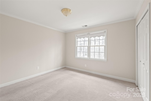 unfurnished bedroom featuring visible vents, baseboards, a closet, crown molding, and light colored carpet