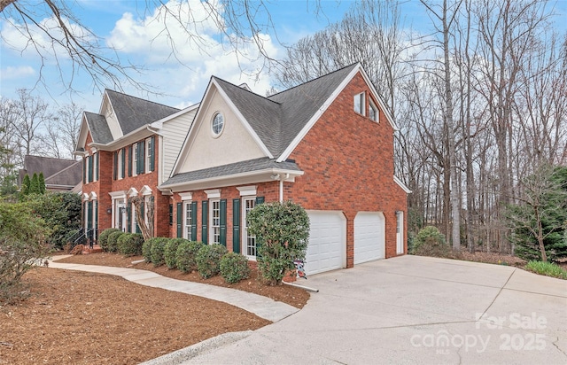 view of side of home featuring brick siding, driveway, a shingled roof, and a garage