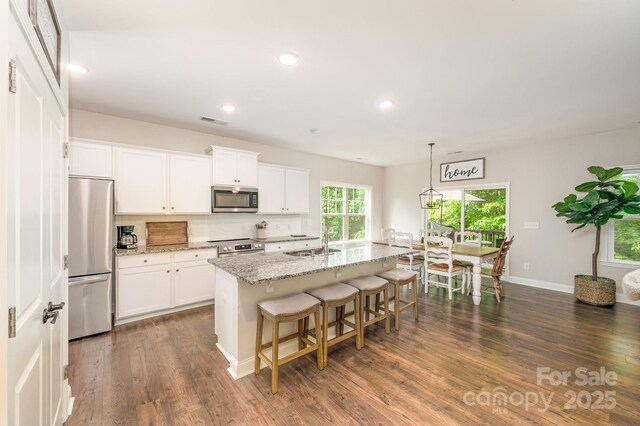 9428 Segundo Ln, Charlotte, NC 28278 - kitchen with stainless steel appliances, backsplash, visible vents, light stone countertops, and a breakfast bar area
