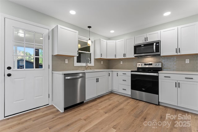 kitchen with light wood-style flooring, appliances with stainless steel finishes, light countertops, and a sink