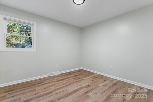 empty room with visible vents, light wood-style flooring, and baseboards