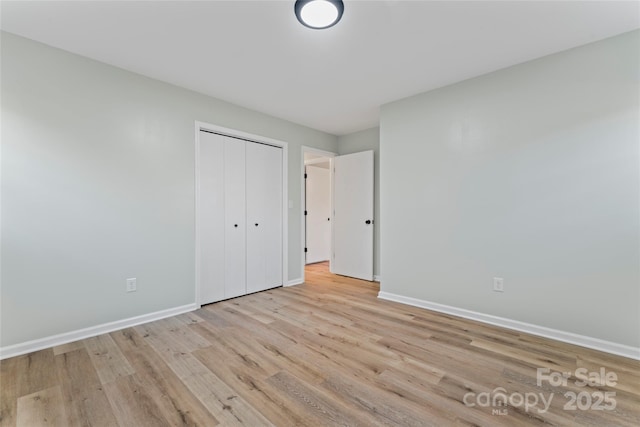 unfurnished bedroom with a closet, baseboards, and wood finished floors