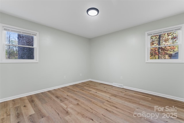 empty room featuring visible vents, baseboards, and wood finished floors