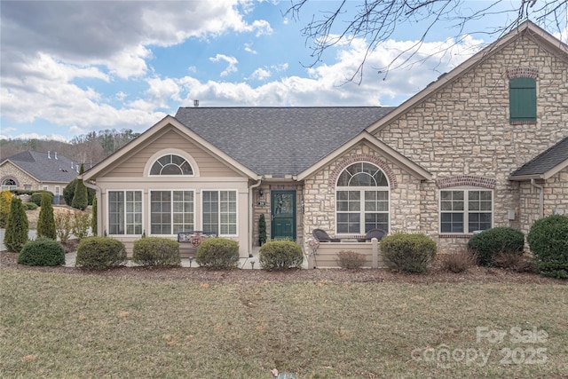 view of front of home featuring a front lawn and a shingled roof