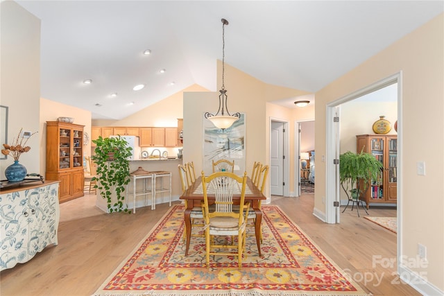 dining space featuring baseboards, lofted ceiling, and light wood-style floors