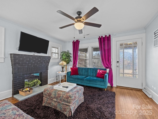 living room featuring baseboards, wood-type flooring, ceiling fan, and a fireplace