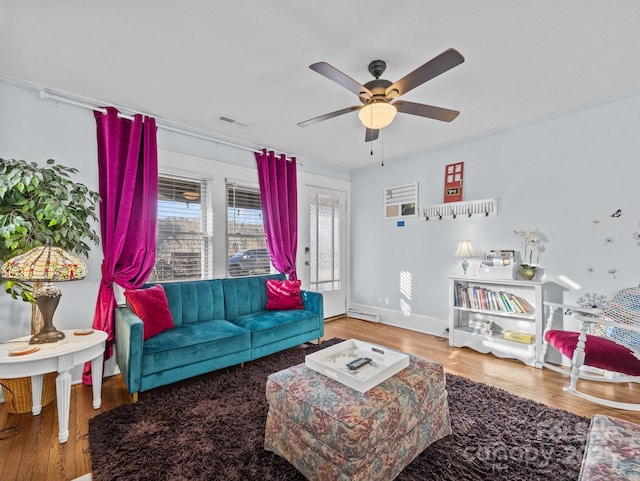 living room with visible vents, wood finished floors, and a ceiling fan