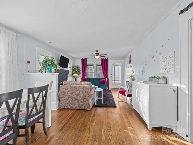 living room with ornamental molding, a ceiling fan, and wood finished floors