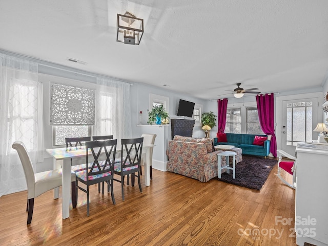 dining space with a wealth of natural light, visible vents, wood finished floors, and ceiling fan