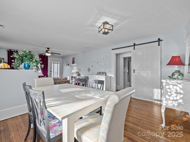 dining area with visible vents, a ceiling fan, wood finished floors, a barn door, and baseboards