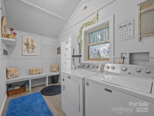 washroom with visible vents, wood finished floors, laundry area, and washer and clothes dryer