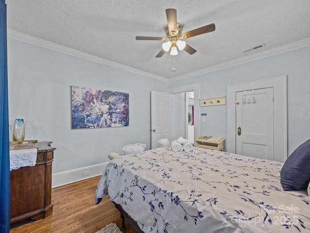 bedroom with a textured ceiling, crown molding, baseboards, and wood finished floors