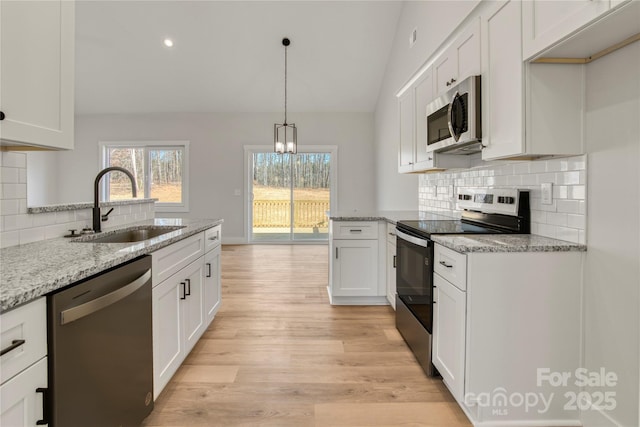 kitchen featuring light wood-type flooring, lofted ceiling, white cabinets, stainless steel appliances, and a sink