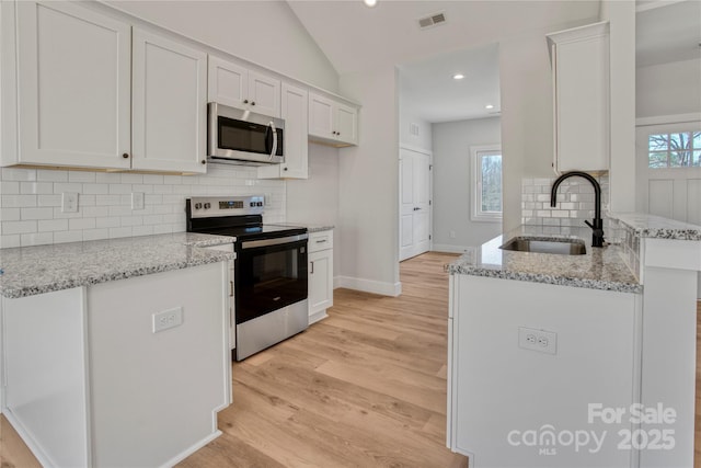 kitchen with visible vents, light wood-type flooring, appliances with stainless steel finishes, white cabinetry, and a sink