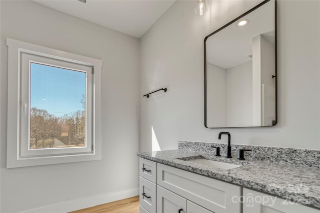 bathroom featuring vanity, wood finished floors, and baseboards