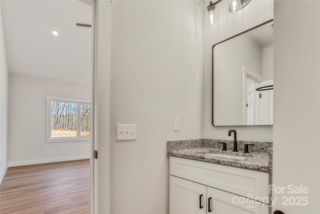 bathroom featuring vanity, wood finished floors, and baseboards