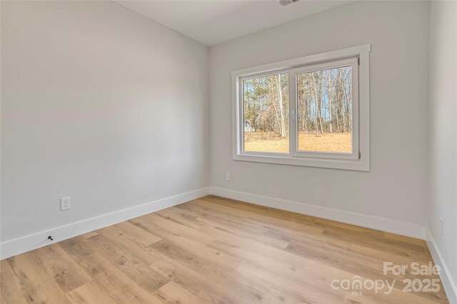 spare room featuring visible vents, light wood-type flooring, and baseboards