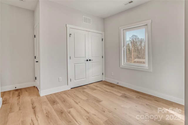 unfurnished bedroom with visible vents, baseboards, a closet, and wood finished floors