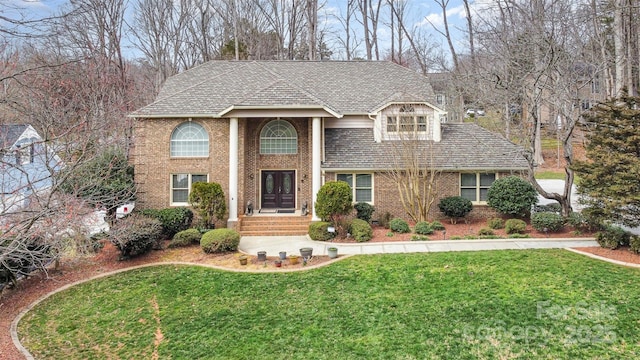 view of front of home with brick siding, french doors, a shingled roof, and a front yard