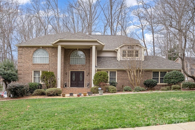 neoclassical / greek revival house featuring brick siding, french doors, a shingled roof, and a front lawn