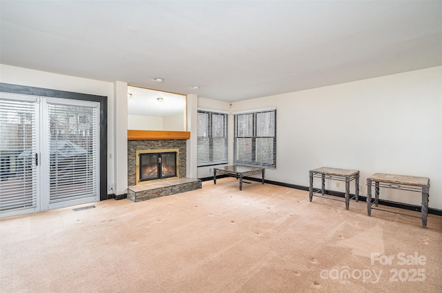 unfurnished living room featuring a stone fireplace, visible vents, carpet, and baseboards