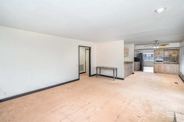 unfurnished living room with visible vents, light colored carpet, a ceiling fan, and baseboards