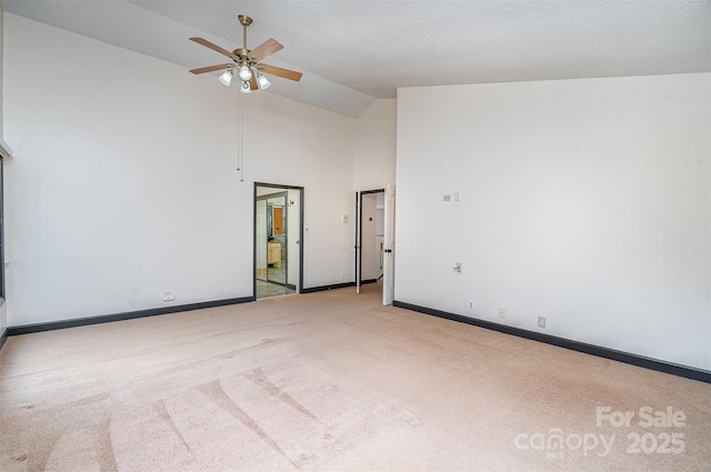 carpeted spare room with a ceiling fan, baseboards, and high vaulted ceiling