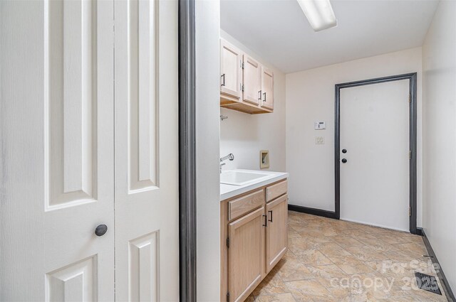 washroom with a sink, cabinet space, hookup for a washing machine, and stone finish floor