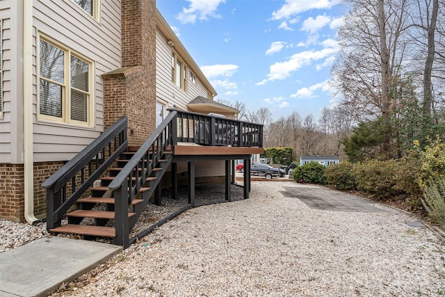 view of side of property featuring a deck, stairway, and brick siding