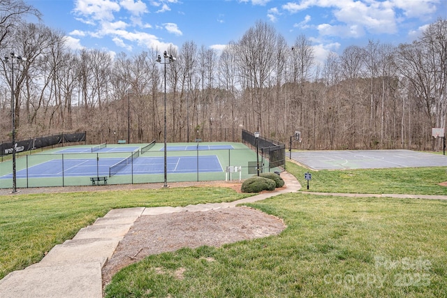 view of sport court with a forest view, a yard, community basketball court, and fence