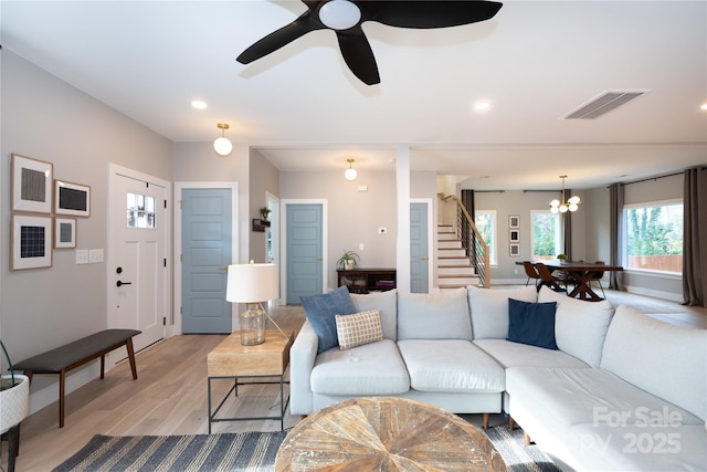 living room featuring light wood finished floors, visible vents, recessed lighting, and stairway