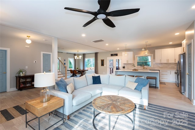 living area featuring stairs, light wood-style flooring, recessed lighting, and visible vents