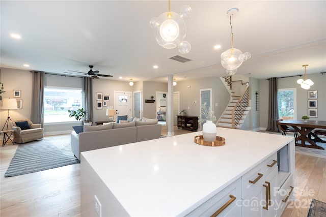 kitchen with white cabinetry, light wood-style flooring, a healthy amount of sunlight, and open floor plan