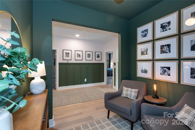 living area with attic access, light wood finished floors, and wainscoting