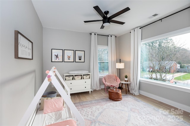 interior space featuring visible vents, ceiling fan, baseboards, and wood finished floors