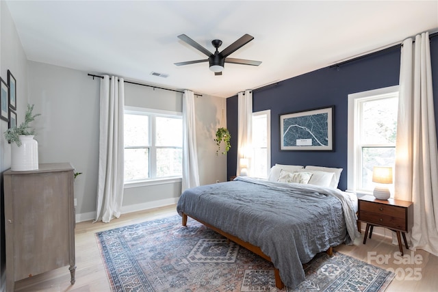 bedroom featuring visible vents, ceiling fan, baseboards, and light wood-style floors