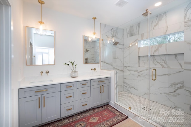 bathroom featuring double vanity, visible vents, a marble finish shower, and a sink