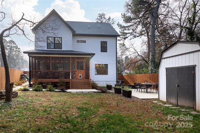 back of house with a storage shed, an outbuilding, a fenced backyard, and a sunroom