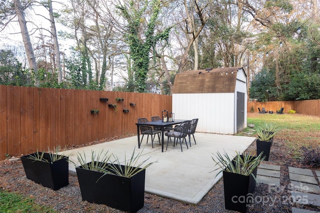 view of patio featuring an outdoor structure, a storage unit, a fenced backyard, and outdoor dining area