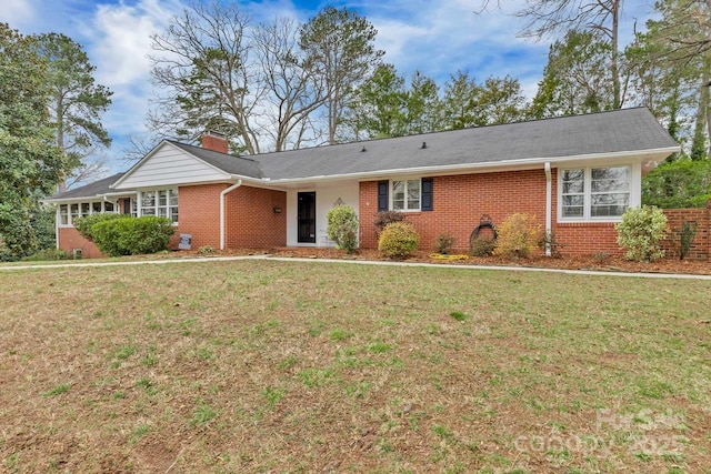 single story home featuring brick siding, a chimney, and a front yard