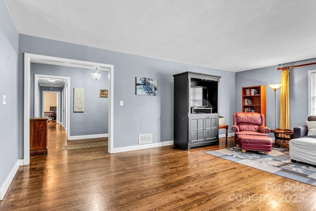 living area featuring wood finished floors, visible vents, and baseboards